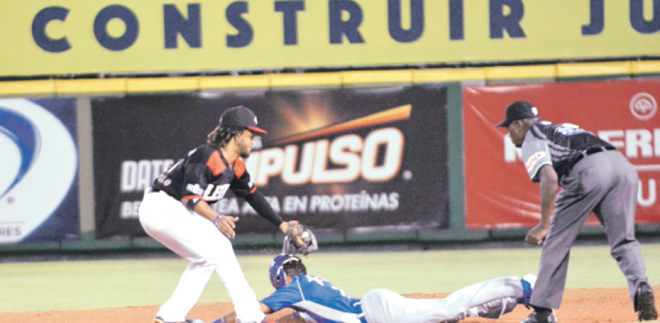 Iván Castillo, de los Leones, pone out en la segunda base a Sergio Alcántara, del Licey, en una jugada originada en la segunda entrada.
