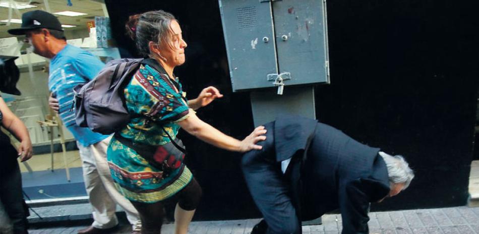 Violencia. Momento en que Iván Aróstica es empujado por una manifestante que lo agredió ayer en el centro de Santiago de Chile.
