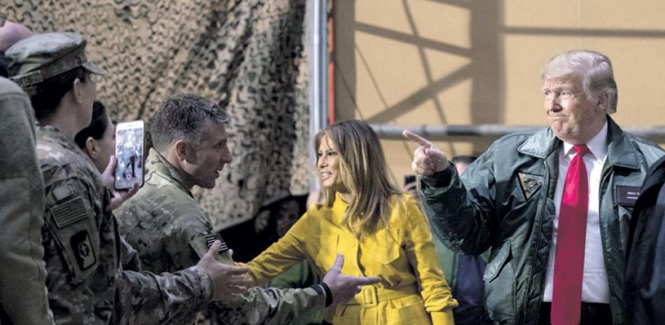 Trompas. El presidente Donald Trump y su esposa Melania saludan ayer a soldados estadounidenses estacionados en Bagdad.