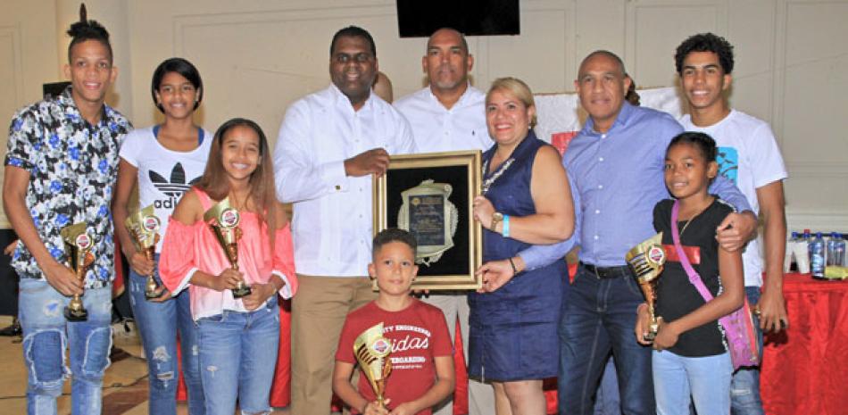 Milton Díaz y Fernando Gómez, presidente y director de Deportes de San Lázaro, junto a Giselle Capellán, sostienen el reconocimiento luego de ser electo como “Club del Año” en el Distrito Nacional, entre otros.