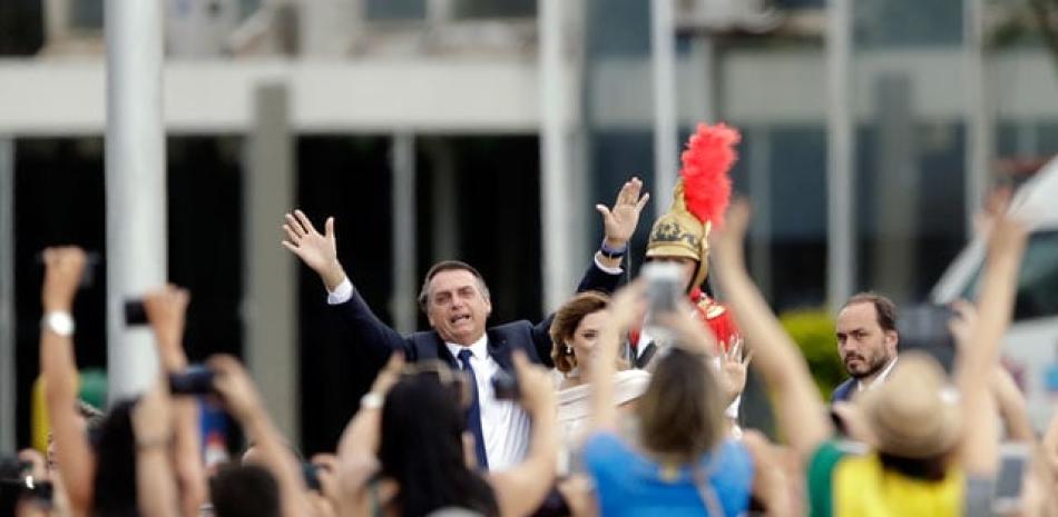 Juramentado. Flanqueado por la primera dama Michelle Bolsonaro, el presidente de Brasil, Jair Bolsonaro, saluda a la multitud mientras viaja en un automóvil abierto después de su ceremonia de juramentación ayer en Brasilia, Brasil. El ultraderechista reafirmó su compromiso con el “rescate de los valores” de la sociedad, una economía de libre mercado y una política exterior “libre de ideologías”.