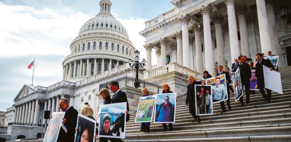 Protesta. El líder de los demócratas en el Senado, Chuck Schumer, izquierda, quien sostiene una fotografía de un trabajador federal, participa en una marcha que pide la reapertura del gobierno federal, ayer.