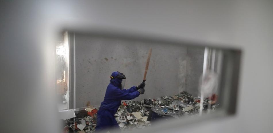 Un cliente de un establecimiento "Anger Room" golpea objetos. La sala, que abrió en la capital china en septiembre de 2018, ayuda a sus clientes a liberar estrés rompiendo botellas, muebles viejos, maniquíes y otros objetos por unos 26 euros media hora, en función de los objetos que se destruyan. EFE/ Wu Hong