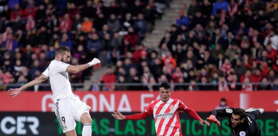 Ofensiva. El omnipresente Karim Benzema, controla la pelota, cuando un defensa y el arquero del Girona le salen al frente.