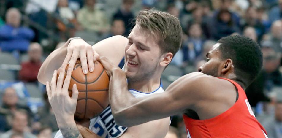 Lucha. Luka Doncic, de los Mavericks, y Mo Harkless, de Portland, luchan por el control del balón en acción del partido de ayer en la NBA.