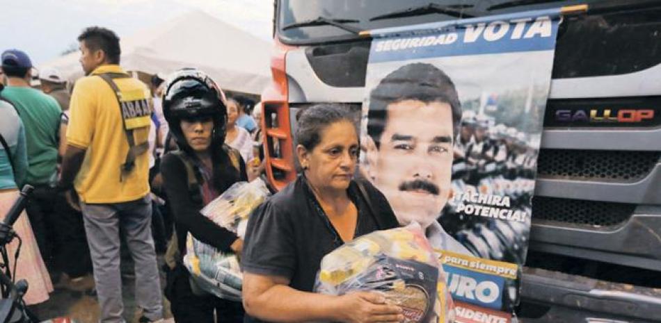 Reparto. Varias personas cargan fundas con alimentos proporcionados por el gobierno de Nicolás Maduro, cerca del puente internacional Tienditas, en las afueras de Ureña, ayer en Venezuela.
