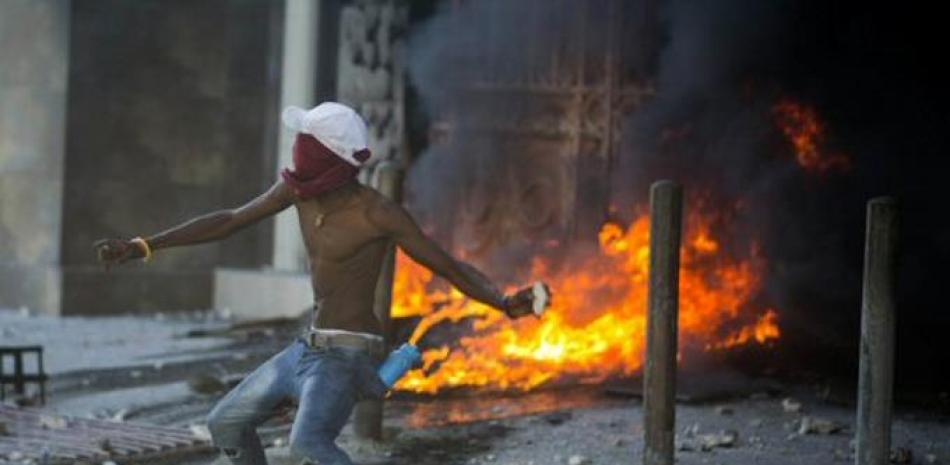 Hombre lanza una roca durante la protestas en Haití.