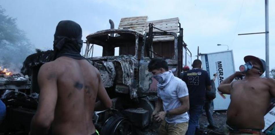 Manifestantes se enfrentan con miembros de la Policía Nacional Bolivariana, junto a un camión que transportaba ayuda humanitaria y fue quemado, este sábado, en el puente Francisco de Paula Santander, en la frontera entre Cúcuta (Colombia) y Venezuela. EFE/ Mauricio Dueñas Castañeda