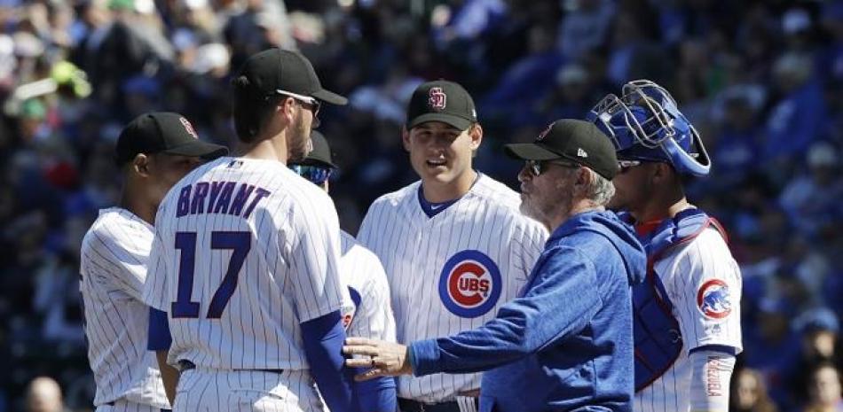 Joe Maddon, manager de los Cachorros de Chicago, conversa con algunos jugadores durante un partido de la pretemporada del béisbol de las Grandes Ligas.
