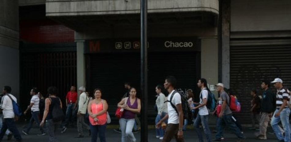 Decenas de personas se desplazan a pie y esperan autobuses debido a la suspensión del servicio del Metro por un apagón este lunes en Caracas.