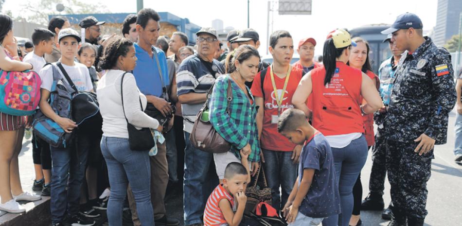 Venezolanos hace fila frente a una parada autobús. EFE