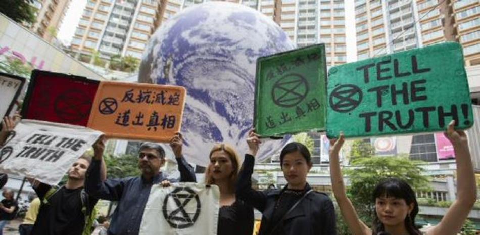 Miembros de la Extinción Rebelión Hong Kong sostienen pancartas que exigen una acción rápida sobre el cambio climático frente a un planeta planeta Tierra gigante en un centro comercial en Tsuen Wan, Kowloon, Hong Kong, China. Foto AP.
