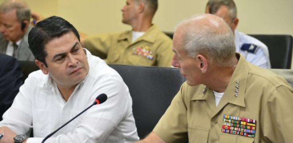 En esta foto de archivo del 6 de agosto de 2014 lanzada por el Departamento de Defensa de los EE. UU., El presidente hondureño Juan Orlando Hernández, a la izquierda, escucha al general de la Marina de los EE. UU., John Kelly, comandante del Comando Sur de los EE. UU.
