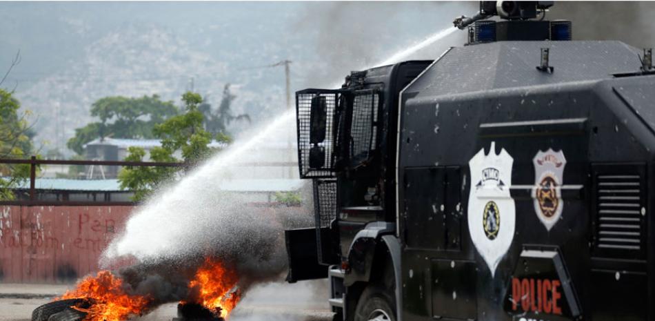 Un cañón de agua de la policía extingue una barricada en llamas cerca del edificio del Parlamento durante una protesta contra la ratificación del Primer Ministro interino Jean Michel Lapin, en Puerto Príncipe, Haití, el jueves 30 de mayo de 2019. (Foto AP / Dieu Nalio Chery)