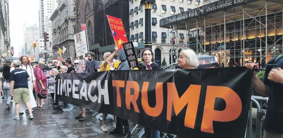 Estadounidenses muestran una pancarta que pide un juicio político contra Trump durante una protesta frente a la Trump Tower en la 5ta. Avenida de Nueva York. EFE