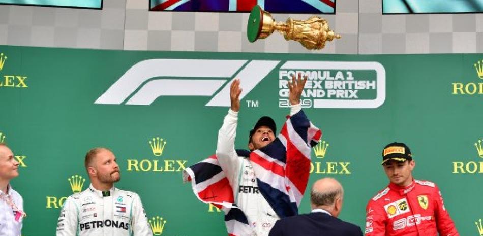 El piloto finlandés de Mercedes, Valtteri Bottas (Izq) observa a Lewis Hamilton lanzar el trofeo al aire en el podio mientras celebra su victoria en el Gran Premio de Fórmula Uno británico en el circuito de carreras de Silverstone.Andrej Isakovic/AFP