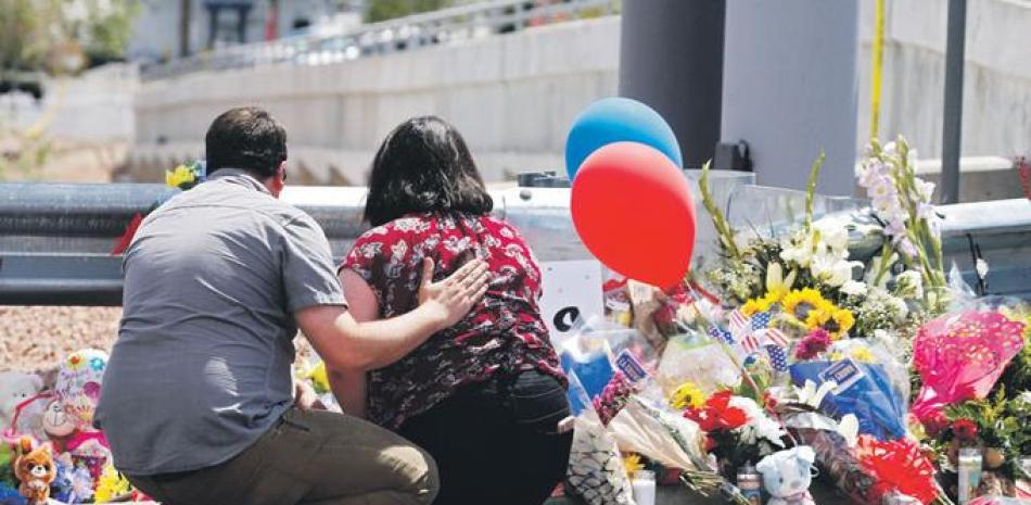 Un hombre consuela a una mujer mientras se arrodilla frente a un memorial a lo largo de la calle detrás de la escena de un tiroteo masivo en un Walmart en El Paso. EFE