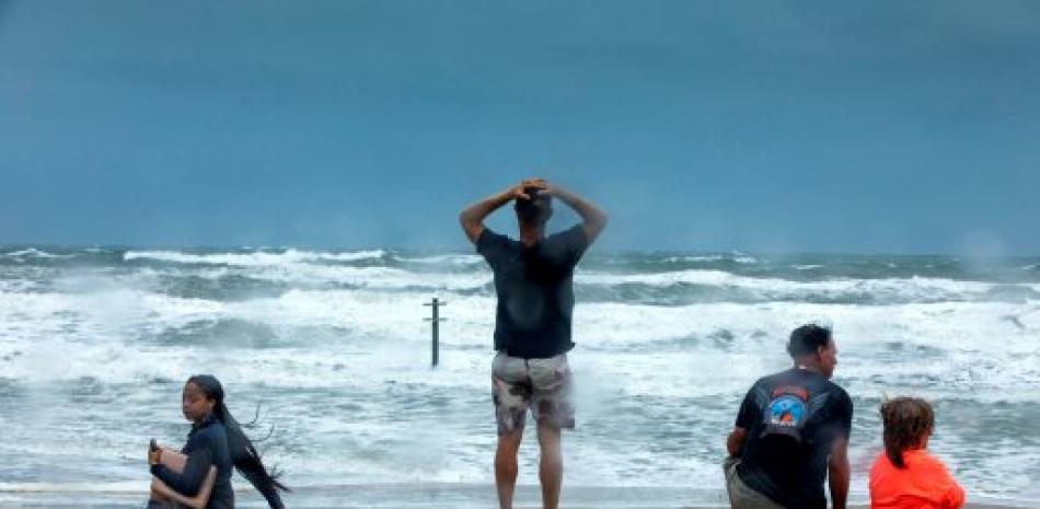 Personas en la Florida observan el oleaje. Foto AP.