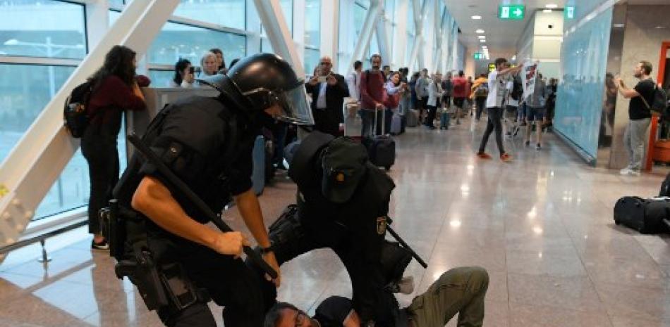 Policías españoles agarran a un manifestante dentro del aeropuerto de El Prat en Barcelona el cuándo miles de protestantes furiosos salieron a las calles después de que la Corte Suprema de España condenó a nueve líderes separatistas catalanes a entre nueve y 13 años de cárcel por sedición por la fallida oferta de independencia de 2017. Lluis Gene/AFP.