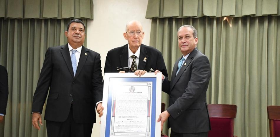 Reinaldo Pared y Euclides Sánchez entregan un pergamino de reconocimiento a Don Cuqui Córdova.