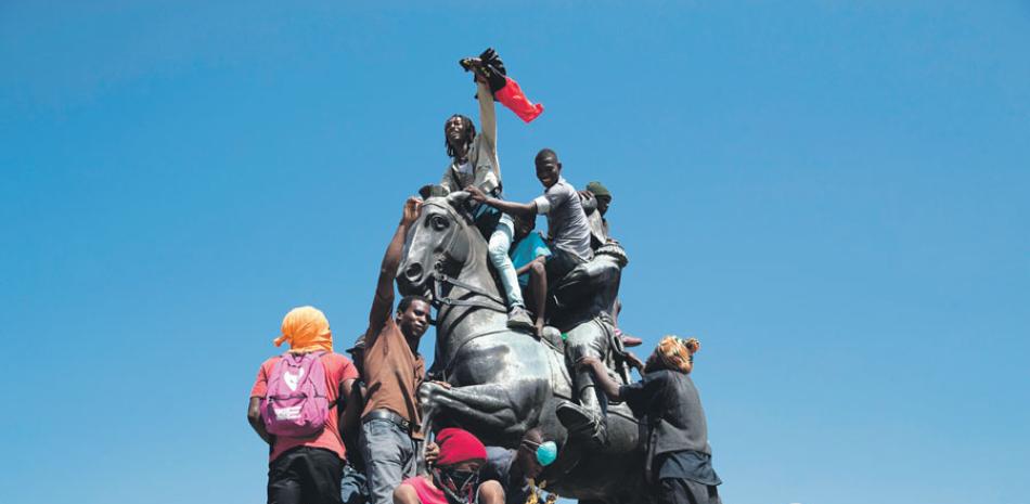 Frente al palacio, manifestantes se subieron a la estatua de Dessalines y reivindicaron la figura del antiguo esclavo, que se proclamó emperador en 1804. EFE/
