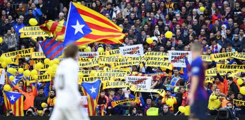 En esta foto de archivo tomada el 28 de octubre de 2018, los fanáticos de Barcelona sostienen pancartas que exigen libertad durante el partido de fútbol de la liga española entre el FC Barcelona y el Real Madrid CF en el estadio Camp Nou de Barcelona. Gabriel Bouys/AFP.