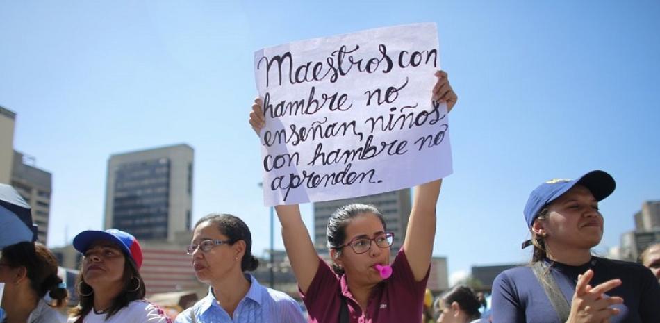 Un maestro sostiene un cartel durante una protesta frente al Ministerio de Educación en el primer día de una huelga de dos días en Caracas, Venezuela, martes 22 de octubre de 2019. (AP Foto / Ariana Cubillos)