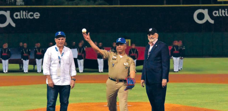 El ministro de Defensa, teniente coronel Rubén Darío Paulino Sem, realiza el lanzamiento de honor del juego. Le acompañan Vitelio Mejía y Domingo Ernesto Pichardo hijo, presidentes de Lidom y Licey, respectivamente.