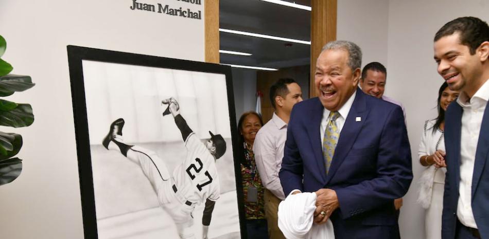 Juan Marichal, acompañado de Yerik Pérez, director de la Oficina de MLB en el país, sonríe mientras contempla el cuadro que develizó con su inigualable estilo de lanzar. GLAUCO MOQUETE / LISTÍN DIARIO