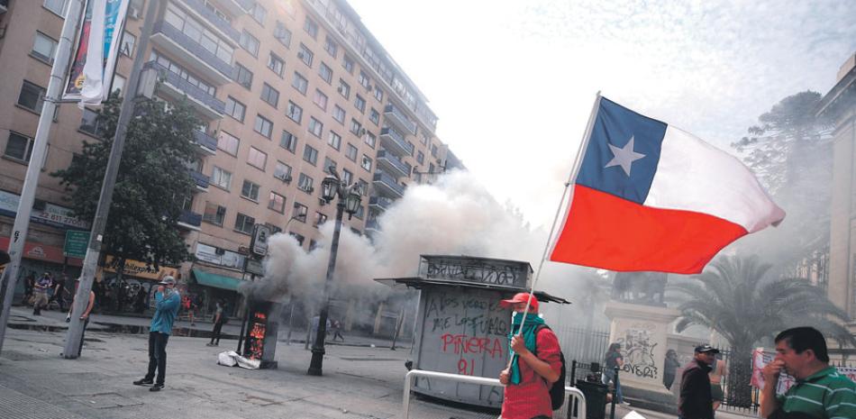 Manifestantes se enfrentan con la policía durante una protesta contra el Gobierno, ayer en Santiago.EFE