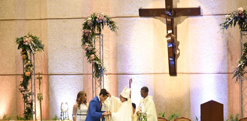 El arzobispo da la bendición a los empleados Laura Sanz y Julio Victoria. JULIO CÉSAR PEÑA /LISTÍN DIARIO.