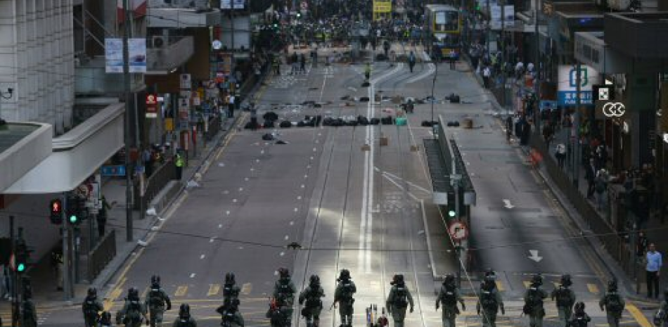 Patrullas de policía recorren el tramo vacío de una avenida de Hong Kong, este lunes, durante una protesta multitudinaria contra la policía en medio de una jornada de huelga en la ciudad autónoma (China).