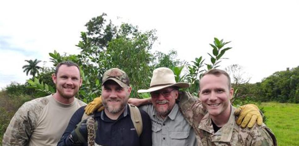 Los veteranos de guerra Shawn Patterson (i), Stan Lake (2i), y David Charles (d) posan con una pitón birmana junto al fundador de la organización Swamp Apes, Tom Rahill (2d), el 9 de noviembre en Los Everglades, Florida.