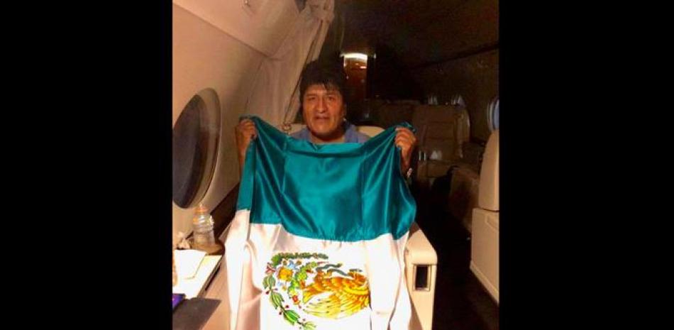 Evo Morales mientras posa con una bandera mexicana, durante su viaje en un avión de la Fuerza Aérea Mexicana. AP