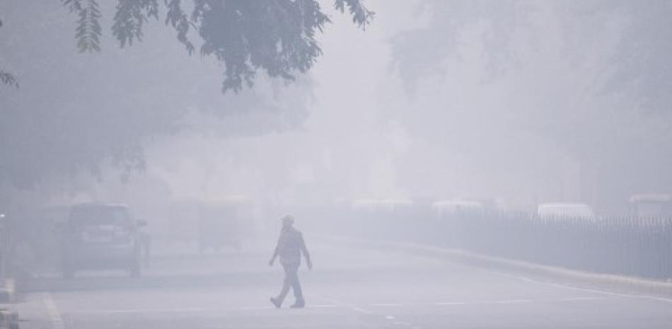 Hombre camina bajo nube de contaminación en Nueva Delhi. / AFP