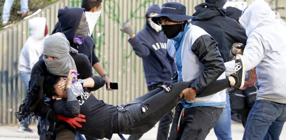 Estudiantes traslandan a joven herido durante las manifestaciones de ayer 26 de noviembre. Foto: AP.