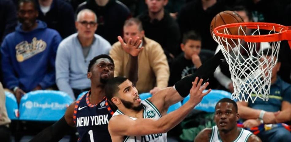 Jayson Tatum, de los Celtics, busca un canasto sobre la defensa de Bobby Portis, de los Knicks, en accióm de ayer en el baloncesto de la NBA.