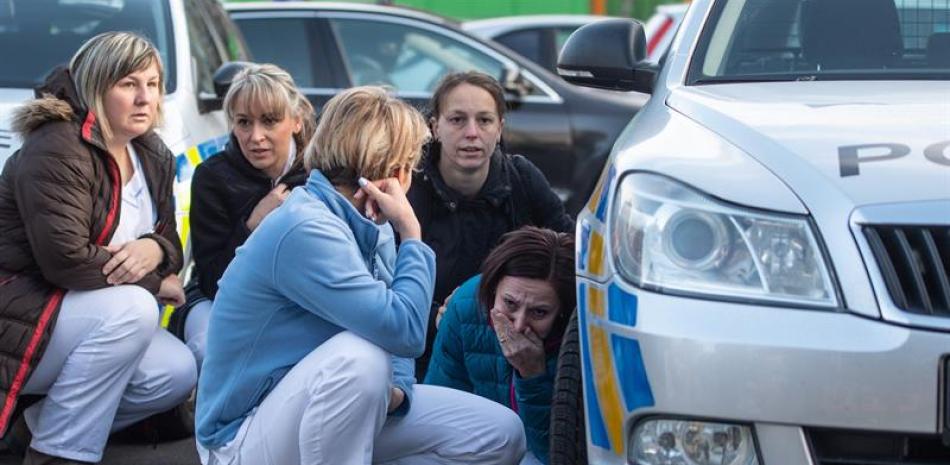 Varias enfermeras se esconden detrás de un coche de policía mientras los agentes perseguían al autor del tiroteo en el hospital de Ostrava (República Checa).  EFE/Lukas Kabon