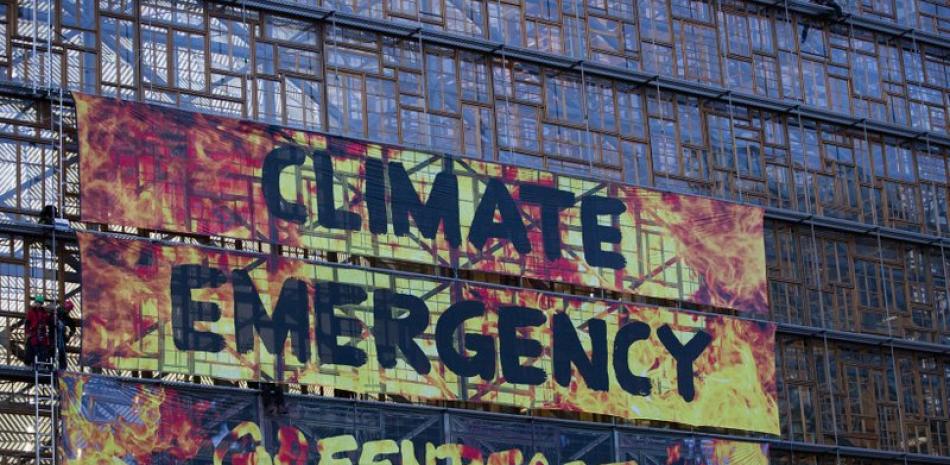 Activistas por el clima, desplegaron una pancarta en un andamio en el Edificio Europa durante una cumbre de la UE, en Bruselas, el 12 de diciembre de 2019. (AP Foto/Virginia Mayo)