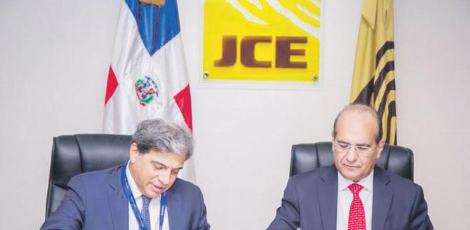 Jaime Guerra, director general y representante legal de la empresa Alhambra Systems, S.A, y Julio César Castaños Guzmán, presidente de la Junta Central Electoral, mientras firmaban el acuerdo para evaluar el sistema de votos.
