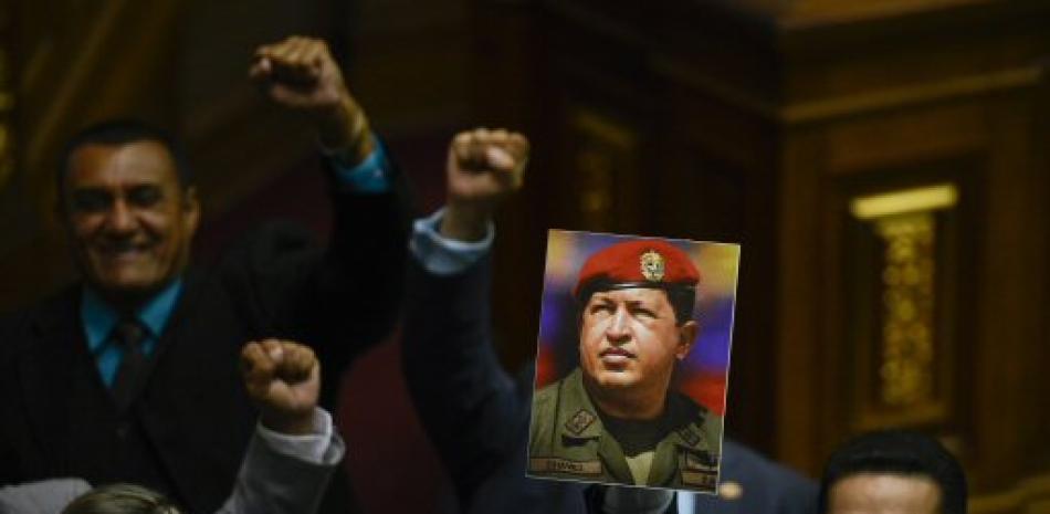 Legisladores a favor del gobierno levantan el puño y gritan que Chávez vive, en referencia al fallecido expresidente venezolano Hugo Chávez, durante una sesión en la Asamblea Nacional en Caracas, el domingo 5 de enero de 2020. (AP Foto/Matías Delacroix)