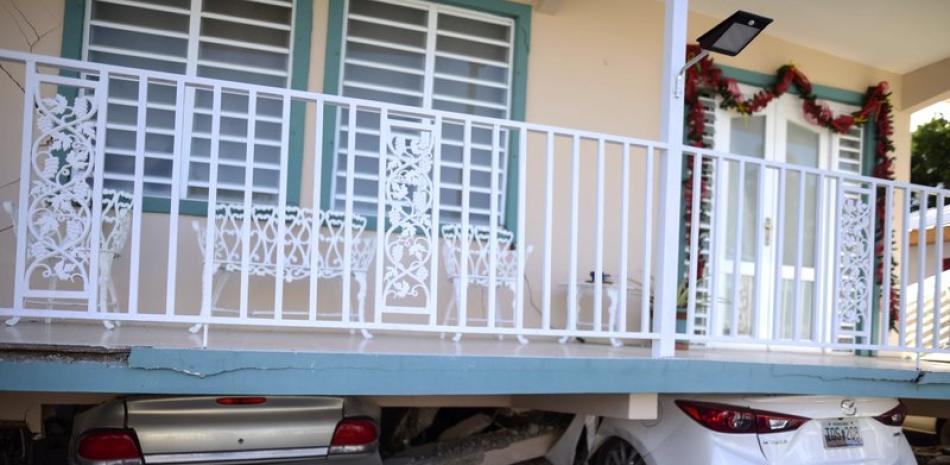 Una vivienda cayó sobre vehículos estacionados después de un terremoto registrado en Guánica, Puerto Rico, el lunes 6 de enero de 2020. Un sismo de magnitud 5,8 remeció Puerto Rico en la madrugada del lunes, provocando pequeños deslaves, cortes en el suministro eléctrico y graves grietas en algunas viviendas. (AP Foto/Carlos Giusti).
