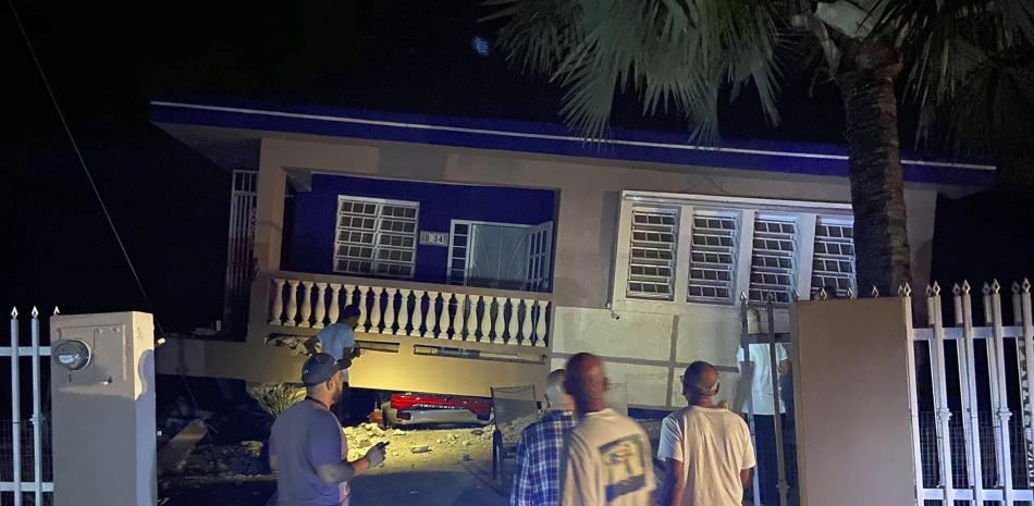 Un edificio derruido con un auto aplastado debajo tras un sismo en Yauco, Puerto Rico, (J. Miguel Santiago Twitter via AP)