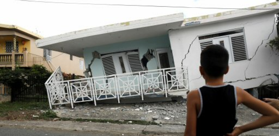 Un niño observa una casa dañada por el temblor. / EFE
