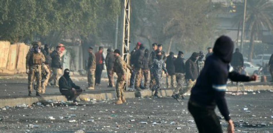 Un manifestante contrario al gobierno lanza una piedra hacia las fuerzas de seguridad durante una protesta en el centro de Bagdad, Irak, el lunes 20 de junio de 2020. (AP Foto/Hadi Mizban)