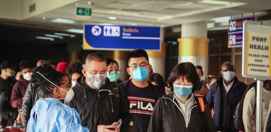 Una empleada de salud examina a pasajeros que acaban de llegar en un vuelo de China Southern Airlines desde Changsha, China, en busca de síntomas del nuevo virus, y que son similares al resfriado común, en el aeropuerto internacional Jomo Kenyatta en Nairobi, Kenia el miércoles 29 de enero de 2020. (AP Foto/Patrick Ngugi)