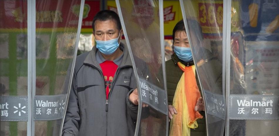 Dos persona saliendo de un supermercado en Beijing, utilizando mascarillas. Foto: AP