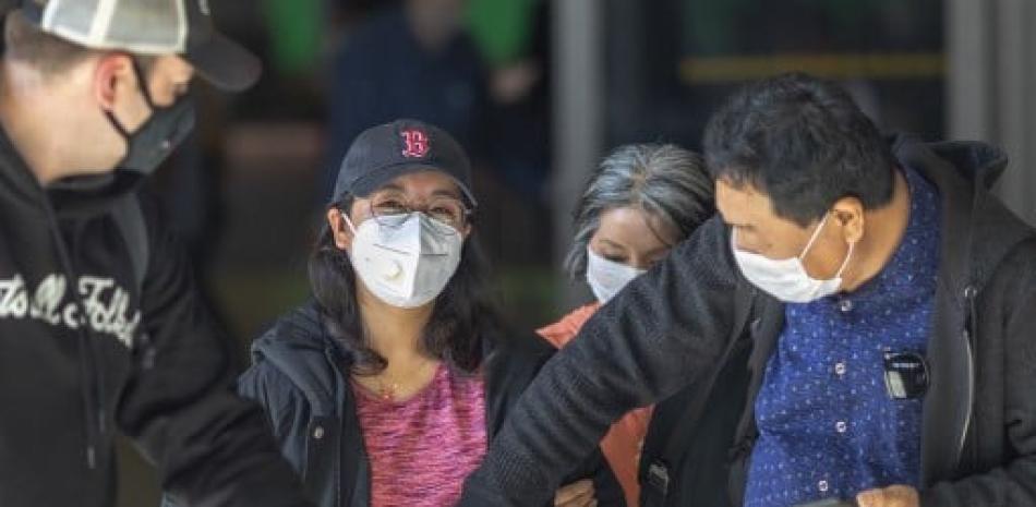 Personas con rasgos chinos en el aeropuerto con mascarillas. / AFP