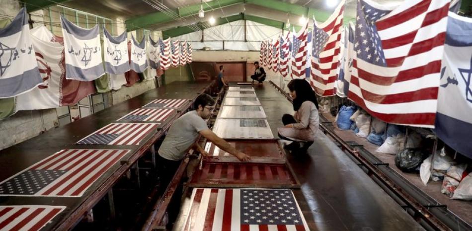 Empleados de la fábrica Diba Parcham Khomein de Heshmatieh, en el centro de Irán, trabajan en la fabricación de banderas de EEUU e Israel que van a ser quemadas en manifestaciones de protesta. Foto del 8 de febrero del 2020. (AP Photo/Ebrahim Noroozi)