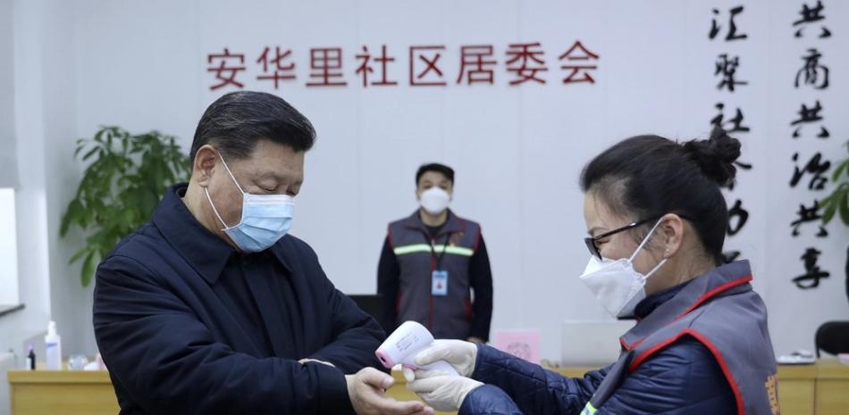 En esta imagen proporcionada por la agencia de noticias Xinhua, el presidente de China, Xi Jinping, a la izquierda con máscara protectora, pasa un control de temperatura corporal antes de visitar un centro de salud en Beijing, el lunes 10 de febrero de 2020. (Pang Xinglei/Xinhua via AP)